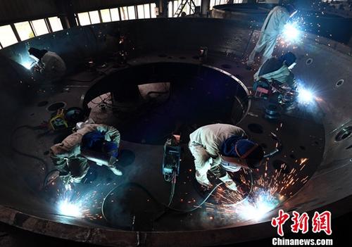 资料图：电焊工人焊接重型机器。/p中新社记者 张斌 摄