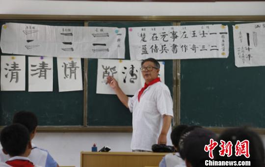 2017年5月25日，‘候鸟型’人才、国家一级美术师李有春为陵水提蒙乡沟尾小学的孩子们传授书法课。(资料图片) 尹海明 摄