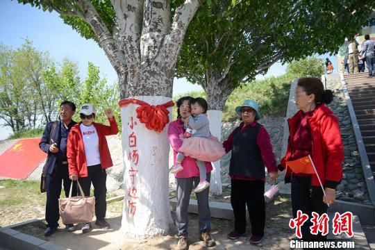 5月10日，第十三届新疆塔城裕民山花节在裕民县小白杨哨所拉开帷幕。游客与小白杨合影。　勉征 摄