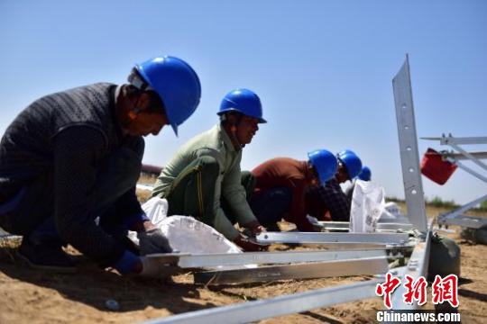 图为工人们头顶烈日进行地面铁塔组装。　云飞翔 摄