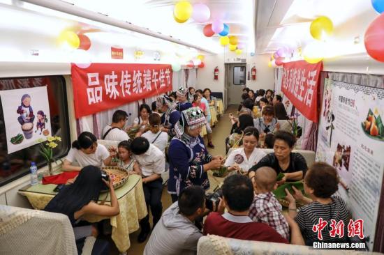 6月4日，在成都铁路局集团公司贵阳客运段广州车队贵阳开往广州的K842次列车车厢内，乘务员与旅客一起，体验包粽子等传统民俗活动，共迎端午节。/p中新社记者 瞿宏伦 摄